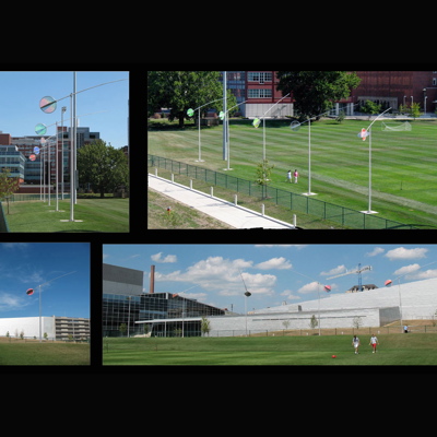 A series of 5 aerodynamic arcs and prismatic discs perform an aerial ballet as they rotate, shift and tilt in the wind. Prismatic discs change color as they catch the light. Sited adjacent to the sports fields of the Recreation and Fitness Facility at Ohio State University in Columbus.Commissioned by the Ohio Percent for Art Program Fabrication: Eastern Sheet Metal Dimensions: 170' X 25’ X 25’